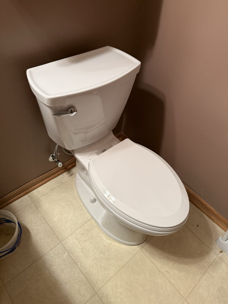 A high-angle, full shot shows a white toilet in a bathroom corner.